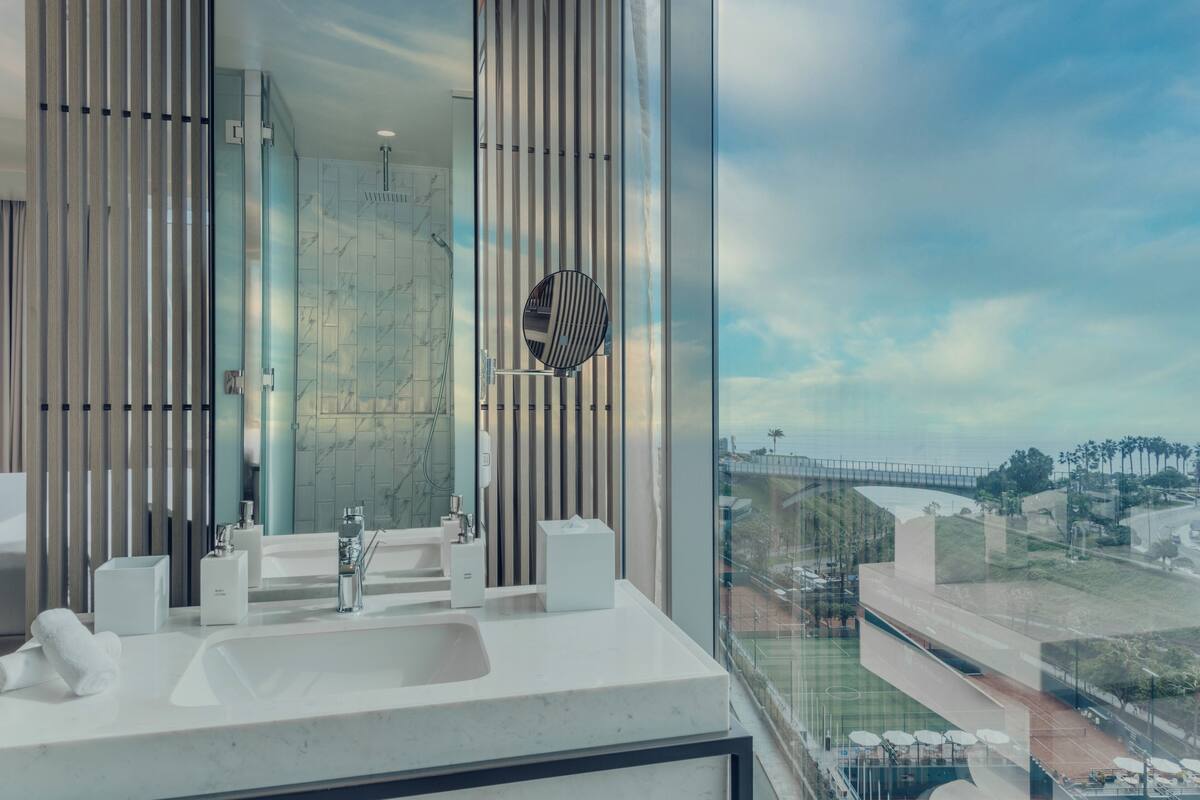 A modern bathroom with a large mirror, a sink, and a shower.