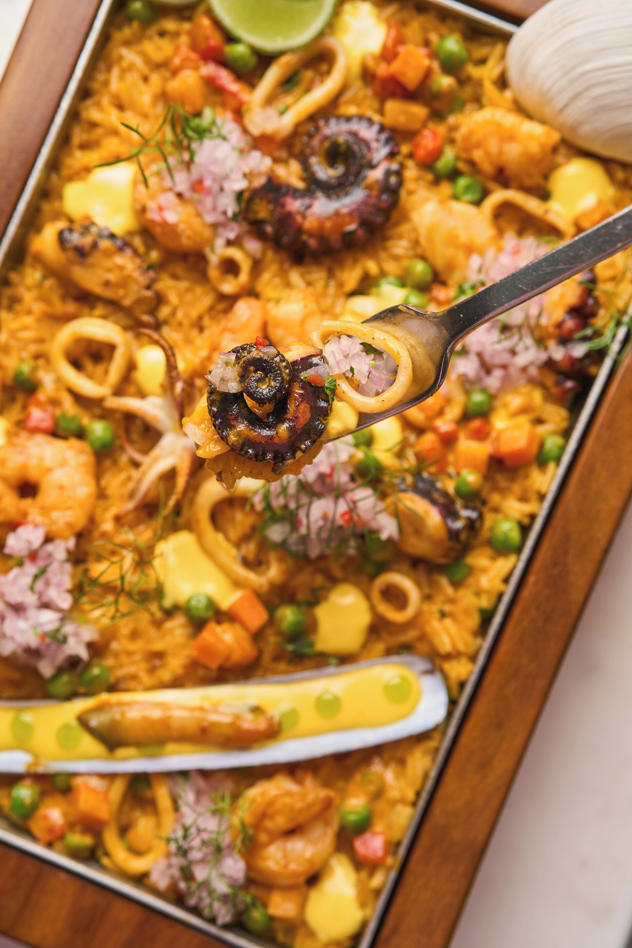 Un grand plat de paella garni de fruits de mer, de légumes et de riz.