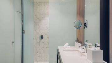 Une salle de bain moderne avec une douche à parois de verre, un pare-baignoire en marbre et un grand miroir.