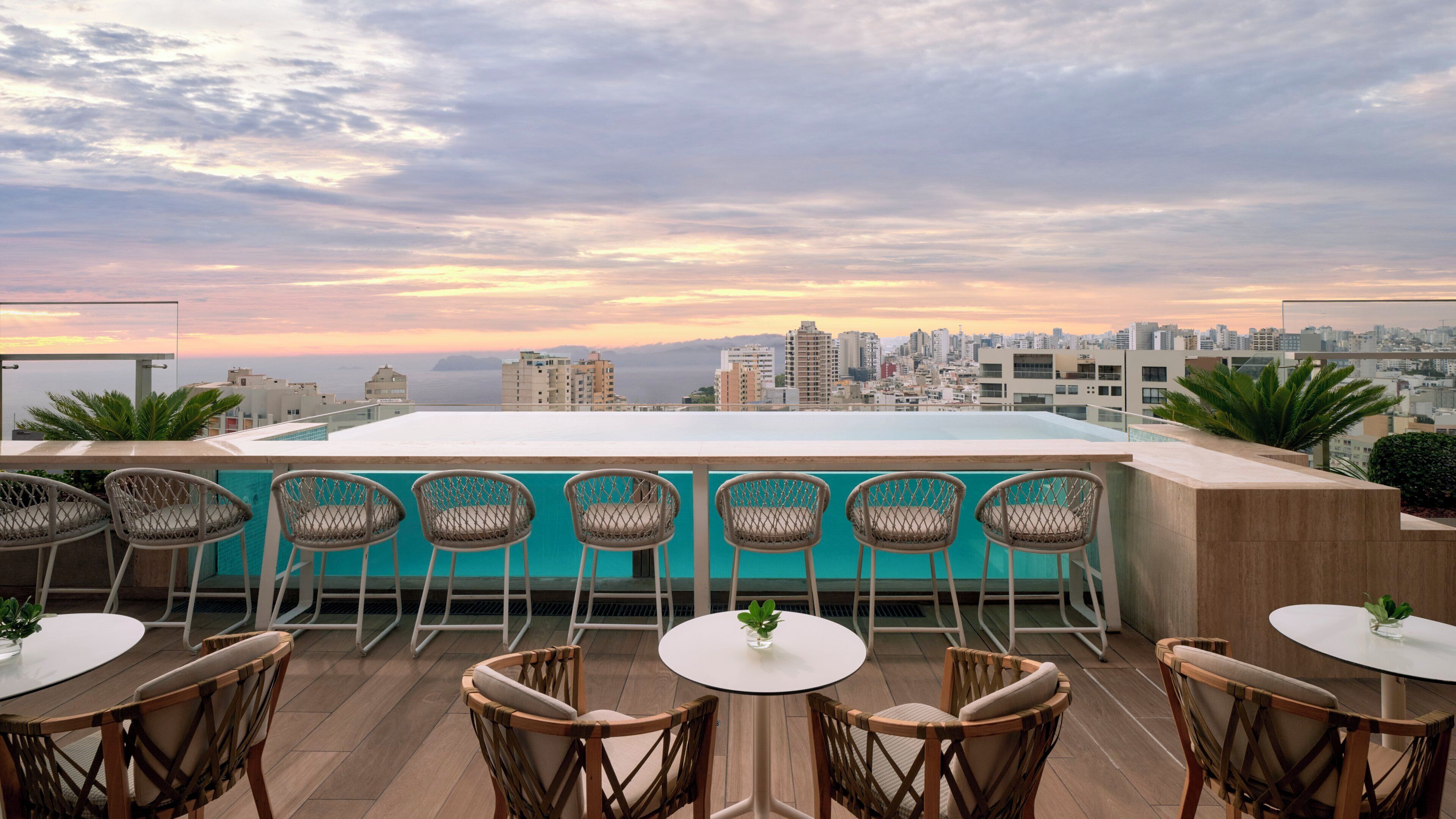 Terraza en la azotea con piscina, zona de estar y vistas a la ciudad.