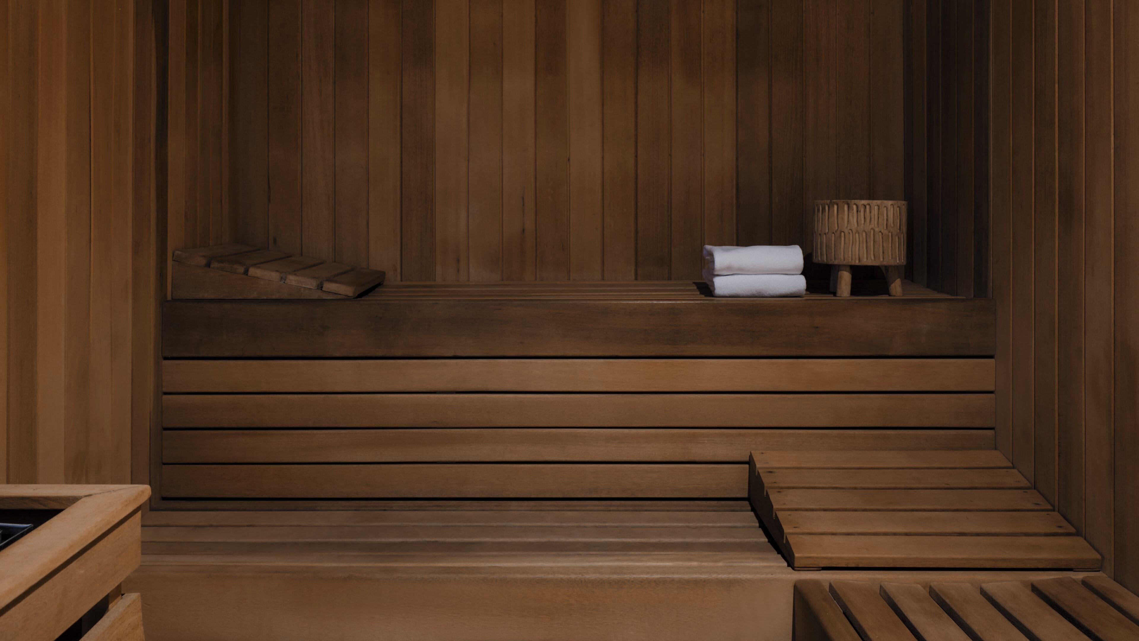 Una sauna de madera con bancos y una pequeña mesa con toallas.