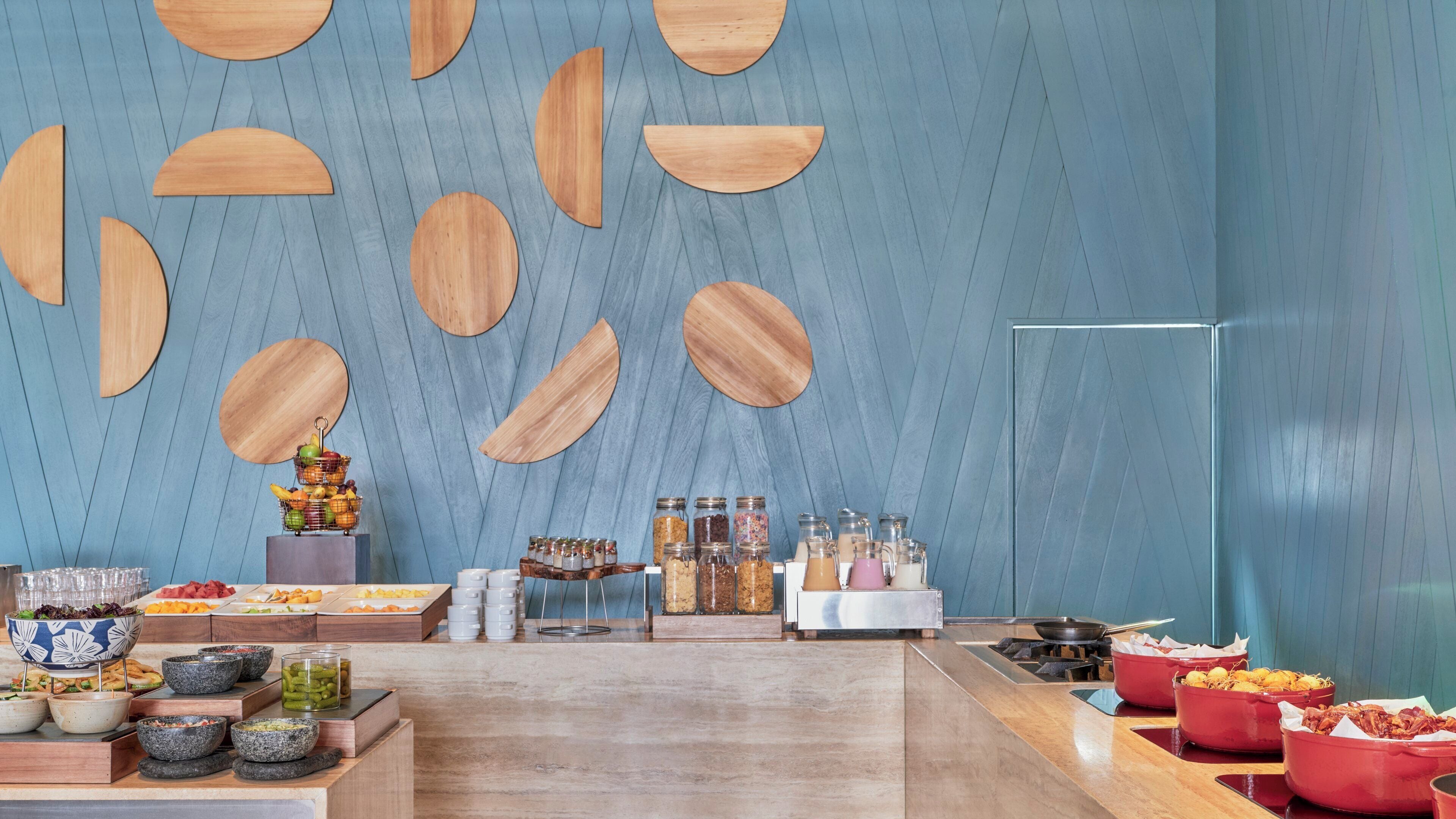 Een moderne keuken met een centraal eiland, houten wanddecoratie en verschillende soorten etenswaren.