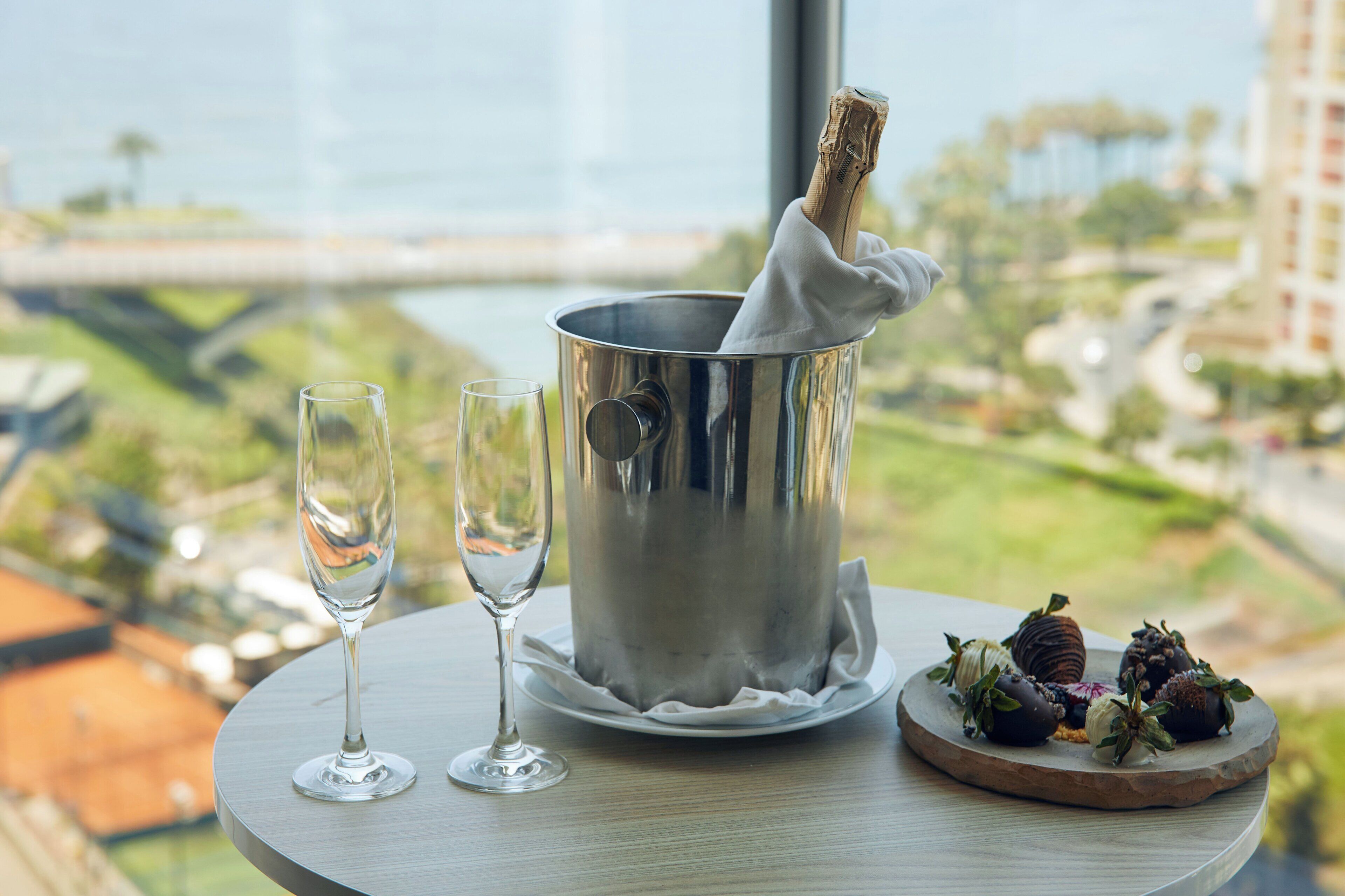 Une table avec une bouteille de champagne, deux verres et une assiette de fruits.