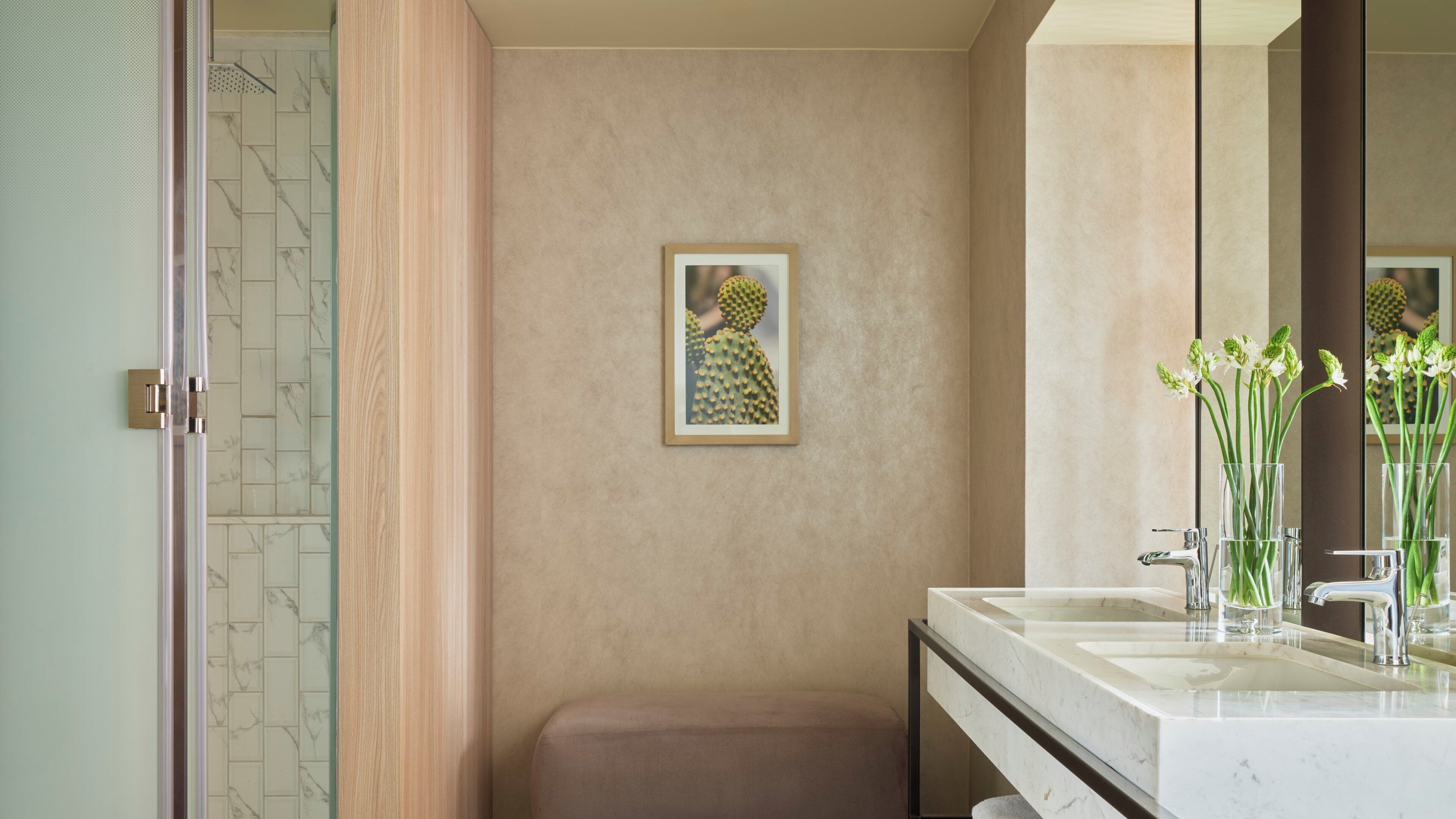 Un baño con un lavamanos de mármol, una obra de arte enmarcada en la pared y un espejo que refleja la habitación.