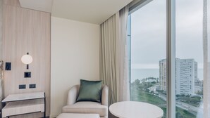 A modern hotel room with a view of the city, a sofa, a small table, and a desk. - Souma Hotel, Vignette Collection by IHG (Lima)
