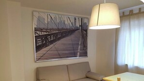 A room with a sofa, a table, a lamp, and a cityscape painting on the wall. - Casa Alpenblick, Centralissimo, Dolomiti (Danta di cadore)