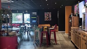 A modern interior with a bar area, seating, and a large screen displaying a movie. - Arl Hotel (Arles)