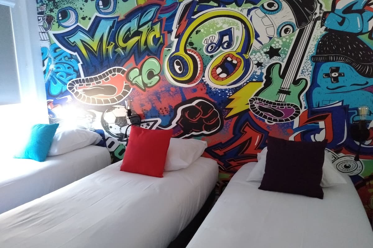 A room with two beds, each with a pillow, and a colorful graffiti wall.