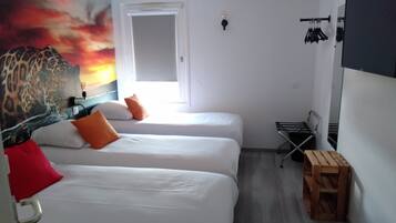A room with two beds, a leopard mural, a window, a wooden stool, and a wall-mounted rack.