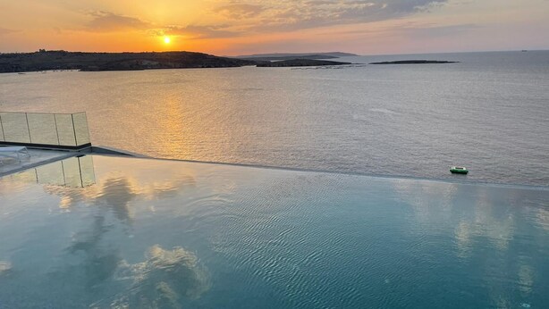An infinity pool with a clear view of the sunset over the water. - Seaview Hotel Malta - Adults Only (St. Paul's Bay)