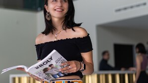 A person holding a magazine in a modern indoor setting with a gold-toned reception desk and a chandelier. - Seaview Hotel Malta - Adults Only (St. Paul's Bay)