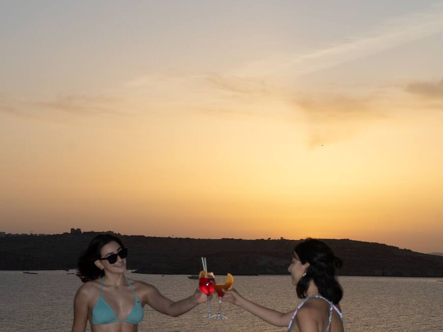 Two people sitting by a pool at sunset.