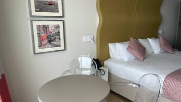 A hotel room with a bed, a round table, and two chairs. There are two framed pictures on the wall.