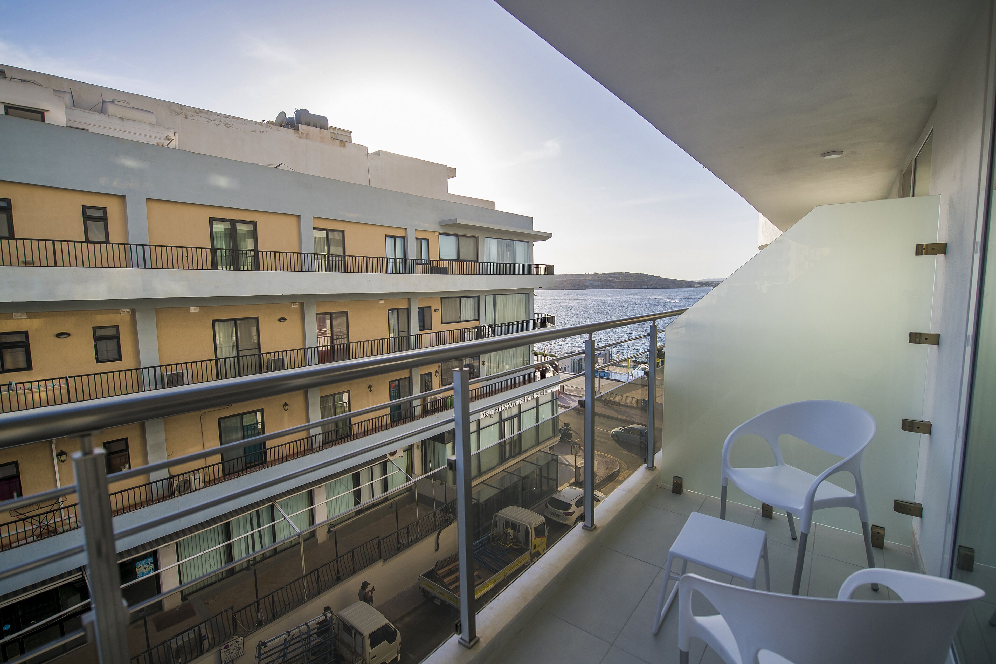 Ein Balkon mit Blick auf ein gegenüberliegendes Gebäude, einem Tisch und zwei Stühlen.