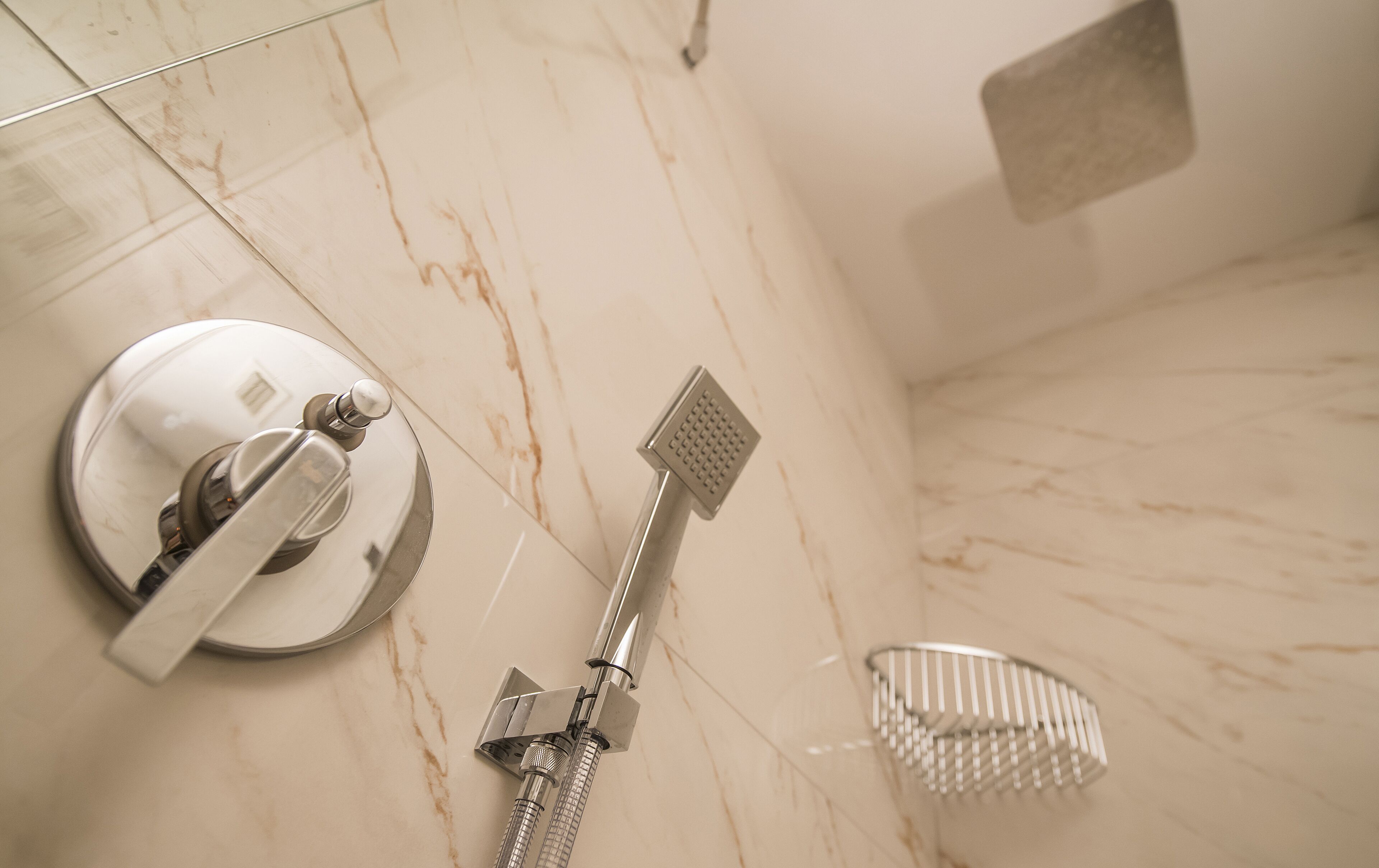 A bathroom with a shower, a hand dryer, and a towel rack.