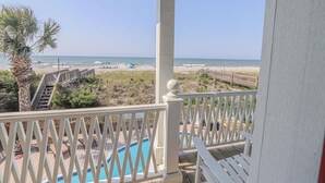 Un balcon avec vue sur une plage et une piscine.