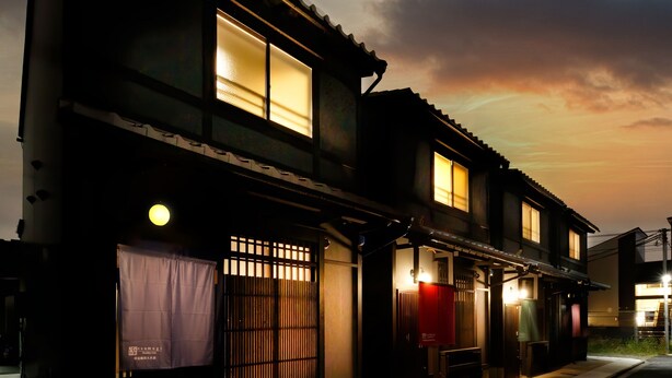 Un edifici japonès tradicional amb diverses finestres, un vestíbul cobert i una petita zona d'estar a l'exterior.
