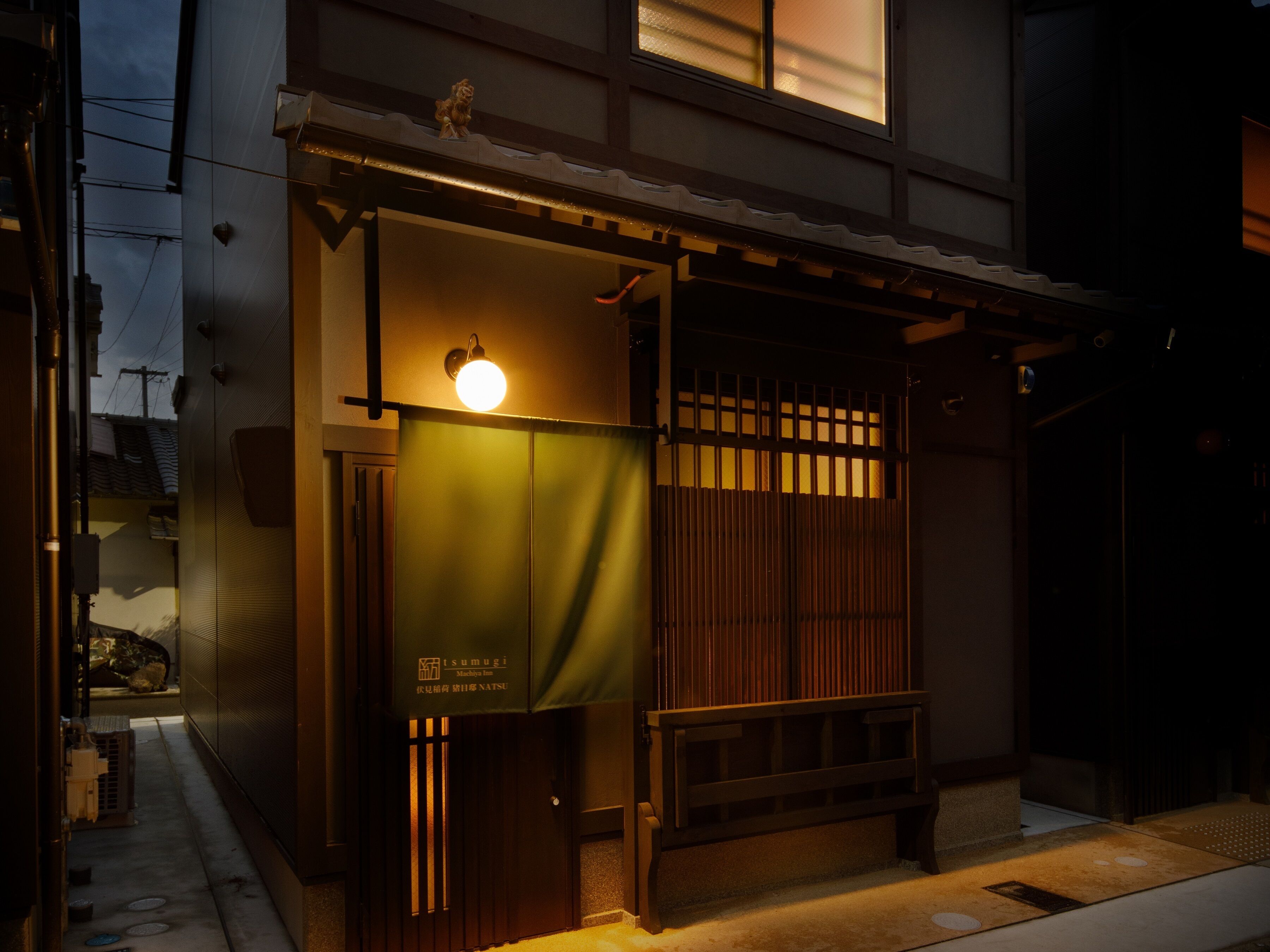 A traditional Japanese-style entrance with a wooden gate, a bench, and a sign for Sumugi Midori Hotel.