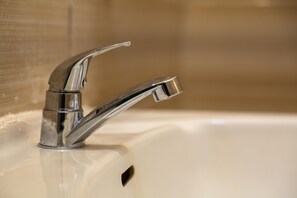 A chrome faucet with a single-handle design on a white sink.