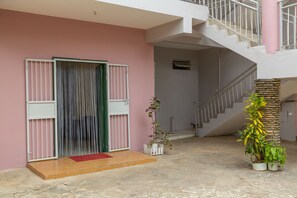 A building entrance with a pink wall, a staircase, and potted plants.