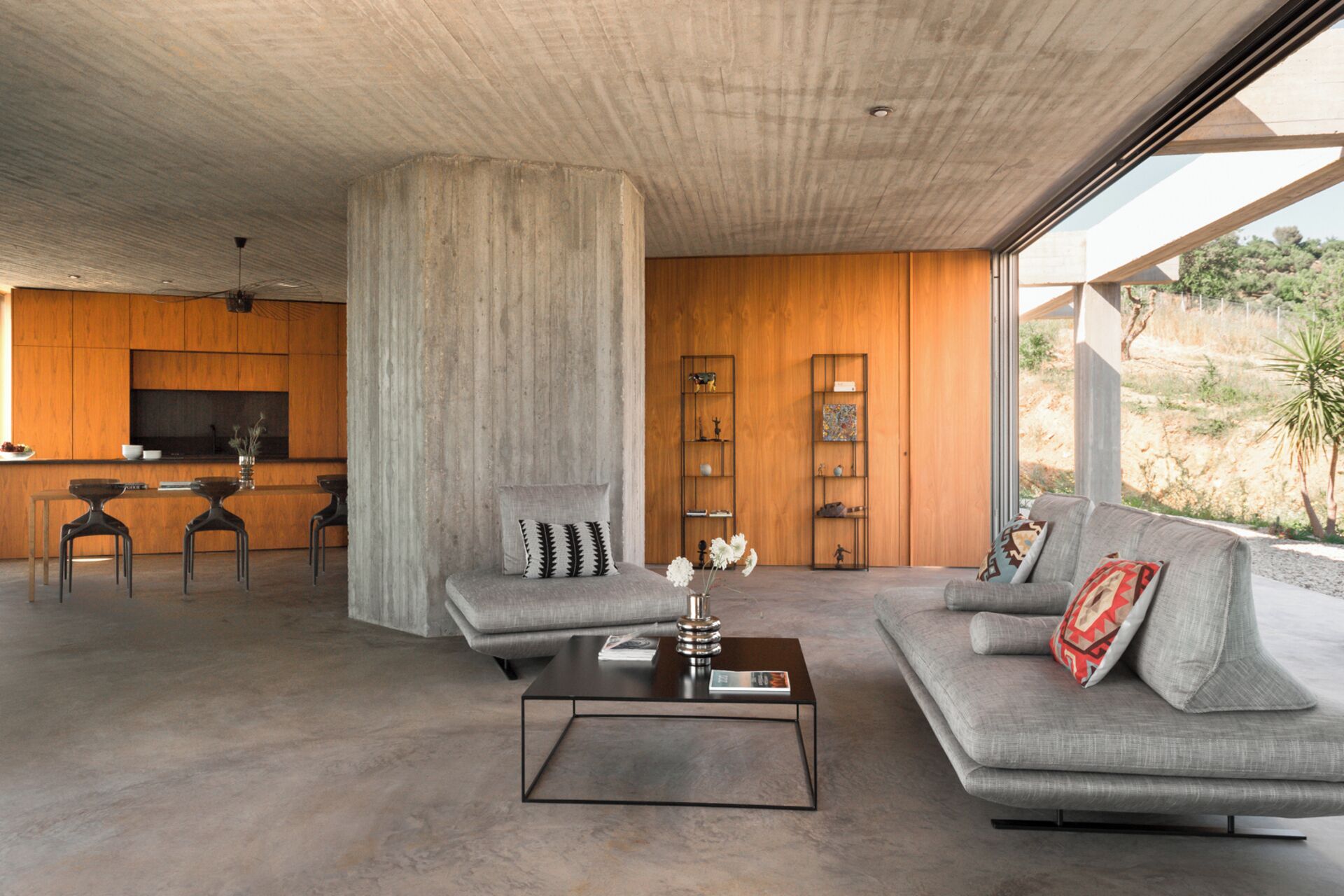 Een moderne woonkamer met een bank, salontafel en een groot raam met uitzicht op de omgeving.