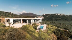 Et moderne hus med pool, omgivet af bakker og bjerge.