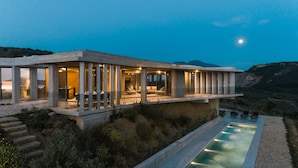 Una casa moderna con piscina, ventanas amplias y vista a las montañas.