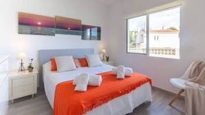A hotel room with a bed, two bedside tables, a chair, and a window with a view of buildings. - Villa El Almendro by Costa CarpeDiem (Calpe)