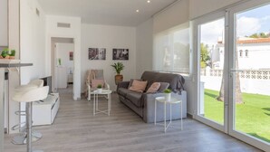 A modern living room with a grey sofa, white coffee table, and a bar area with a white stool. - Villa El Almendro by Costa CarpeDiem (Calpe)