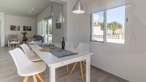 A modern dining area with a white table, chairs, and pendant lighting. - Villa El Almendro by Costa CarpeDiem (Calpe)