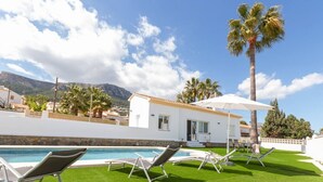 A pool area with lounge chairs, a small building, and palm trees. - Villa El Almendro by Costa CarpeDiem (Calpe)