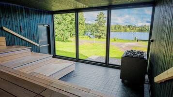 A modern interior with a wooden bench, a fireplace, and a large window overlooking a lake.