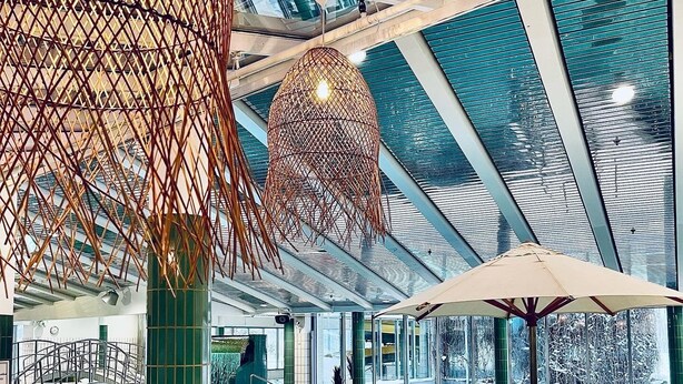 Modernilla designilla varustettu sisäuima-allas, jossa on lasikatto ja geometriset valaisimet.