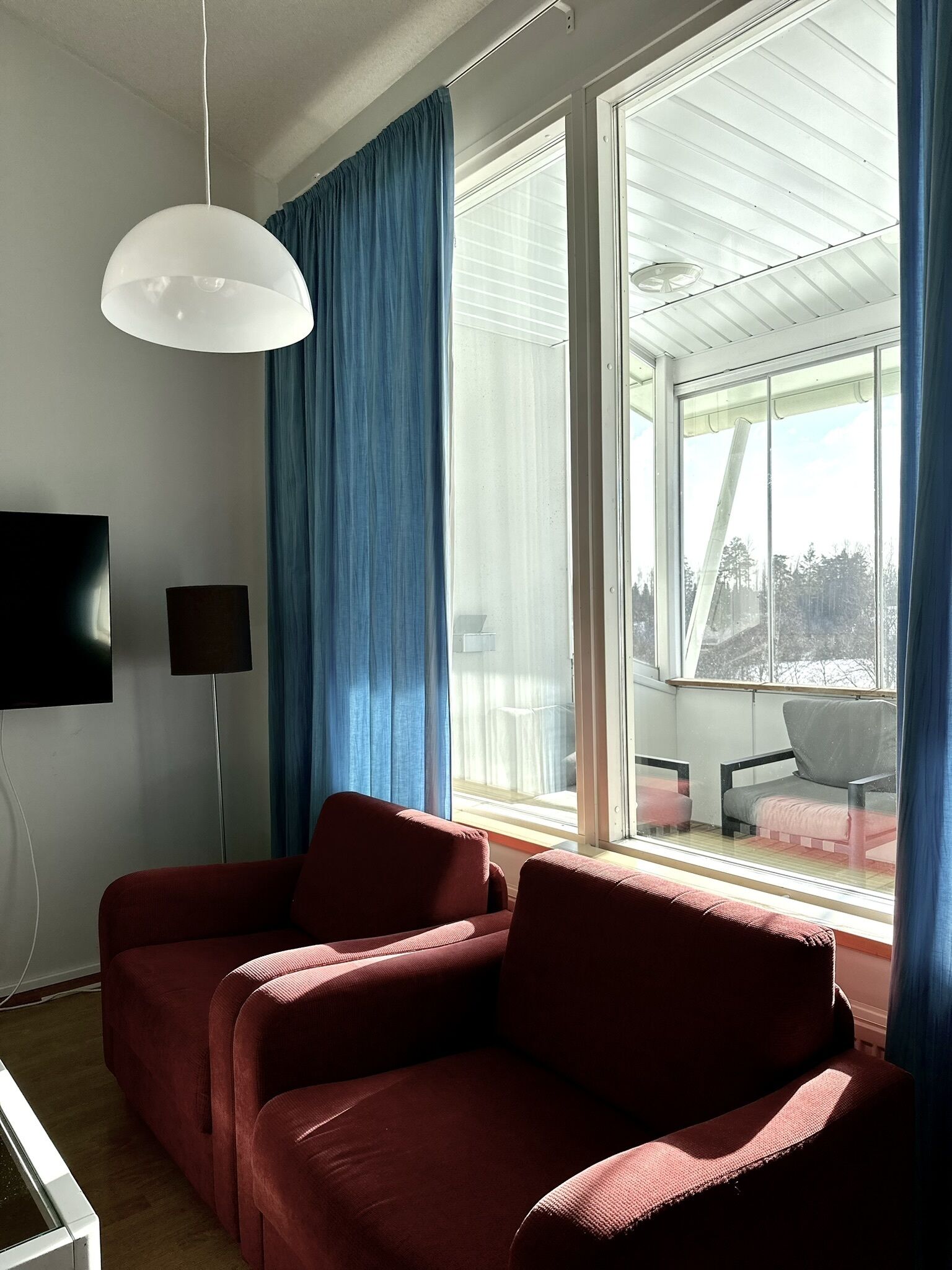 A modern living room with a sofa, a floor lamp, and a television.