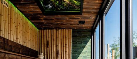Un interior moderno con un banco de madera, un muro de vidrio y un techo con iluminación natural.