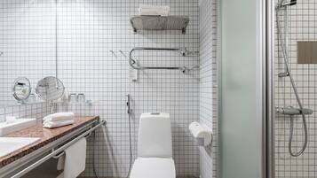 A modern bathroom with a white toilet, a sink with a granite countertop, a mirror, and a shower area.