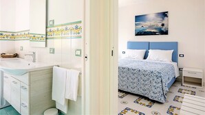 Un bagno con lavandino, specchio e un asciugamano appeso al muro.