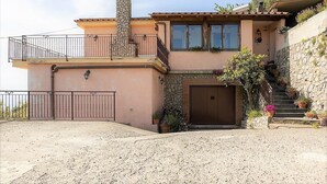 Una casa a due piani con un camino in pietra, un balcone e un garage.