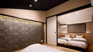 Una habitación de estilo japonés tradicional con suelo de tatami, un panel corredero shoji y una cama con dos almohadas.