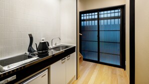 Una cocina con paredes de azulejos blancos, encimera negra y una estufa. Se ve una ventana con vistas a edificios.