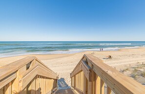 A wooden boardwalk leading to a sandy beach with the ocean in the background.