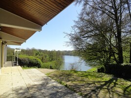 Un espace extérieur abrité offrant une vue sur un lac et des arbres.