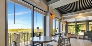 A balcony with a table and chairs, large windows, and a ceiling with a striped pattern. - OV 921 Golf Course View Condo - Paradise Rental in Ocean Village (FORT PIERCE)