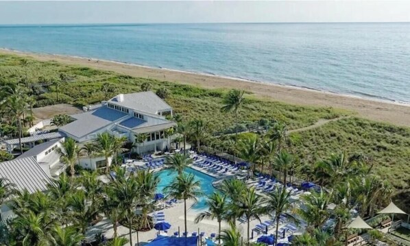Ein Resort mit Pool, Meerblick und Palmen.