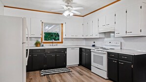 A modern kitchen with black and white cabinetry, a built-in oven, and a ceiling fan.