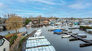 A marina with boats docked, a bridge, and buildings along the riverbank.
