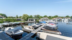 A marina with various boats docked, a wooden dock, and houses in the background. - Spacious and luxurious apartment - Kaag Resort (15) (Warmond)
