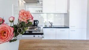 A modern kitchen with white cabinets and a wooden countertop. - Spacious and luxurious apartment - Kaag Resort (15) (Warmond)