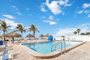 Ein Pool mit Liegestühlen und Palmen.