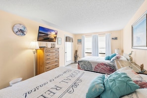 Ein Schlafzimmer mit einem Bett, einem Schminktisch, einer Uhr und einem Bild an der Wand.